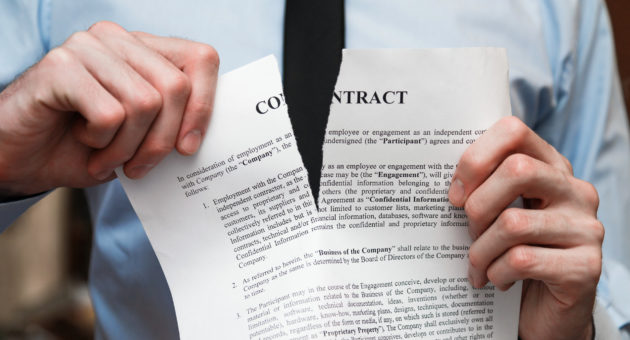 person tearing a paper representing a breach of contract