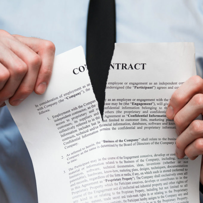 person tearing a paper representing a breach of contract