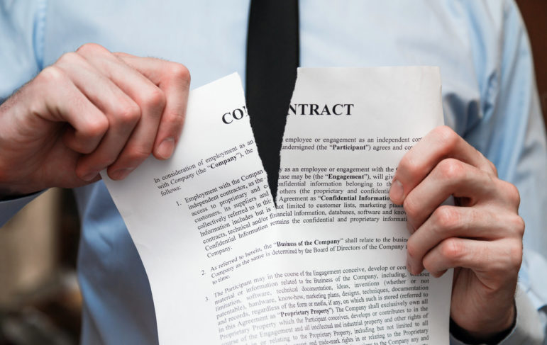 person tearing a paper representing a breach of contract