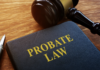 Close-up of a legal book titled “Probate Law” on a wooden desk beside a judge’s gavel and a pen