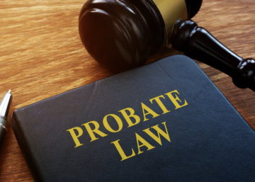 Close-up of a legal book titled “Probate Law” on a wooden desk beside a judge’s gavel and a pen