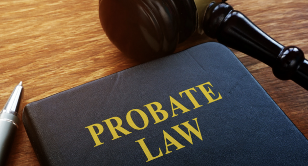 Close-up of a legal book titled “Probate Law” on a wooden desk beside a judge’s gavel and a pen
