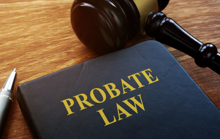 Close-up of a legal book titled “Probate Law” on a wooden desk beside a judge’s gavel and a pen