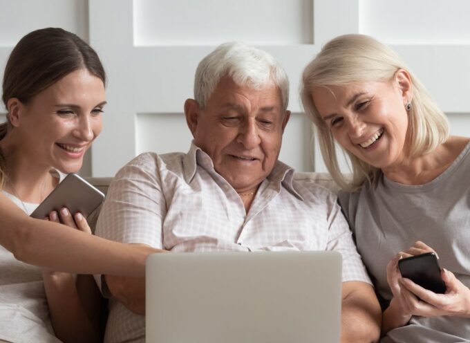 three people sitting on a couch looking at a computer while laughing and smiling and pointing to it